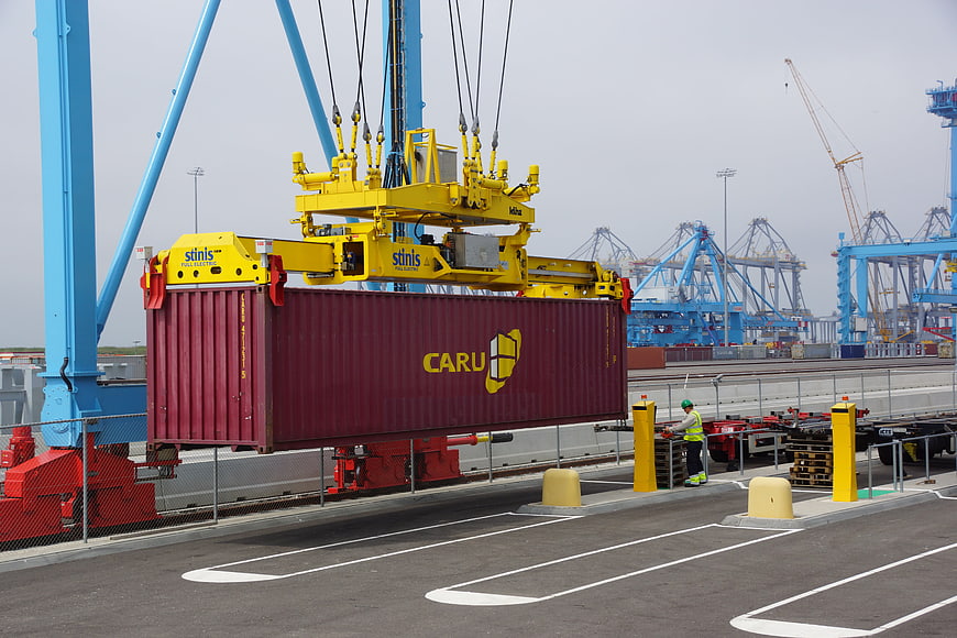 Automated crane lifting red shipping container at port