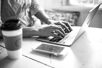 Woman Typing on Laptop with Coffee and Smartphone