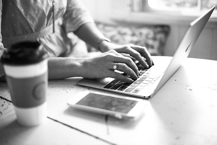 Woman Typing on Laptop with Coffee and Smartphone