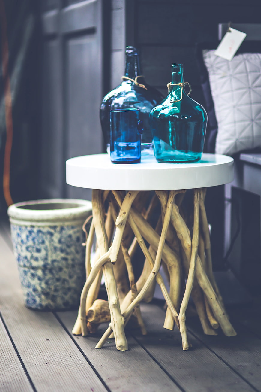 Rustic driftwood table with blue glass bottles on deck