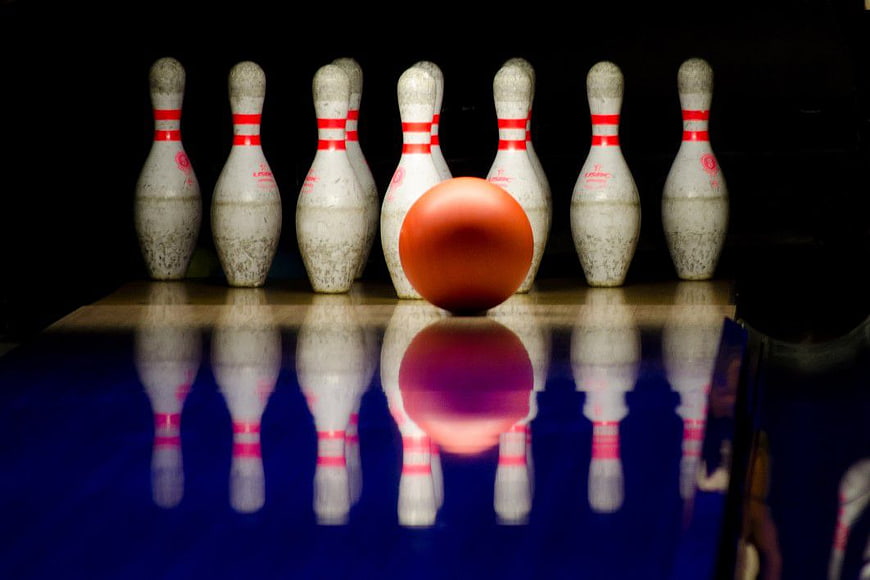 Orange Bowling Ball and Pins on Reflective Lane