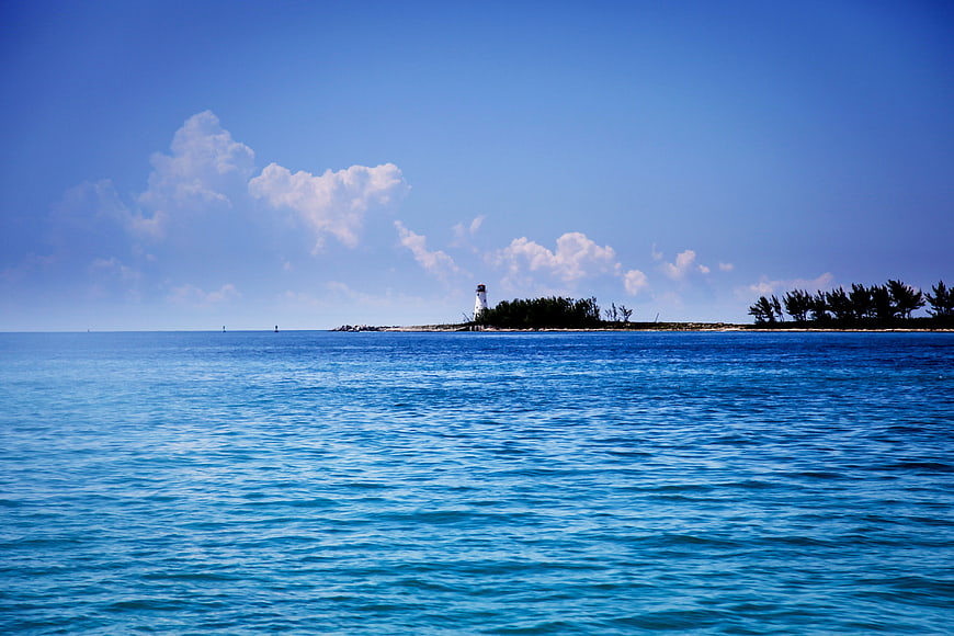 Lighthouse on tropical island with blue ocean and sky