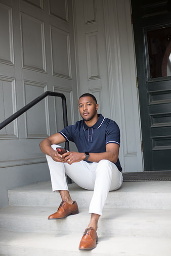 Stylish Black Man Sitting on Steps with Smartphone