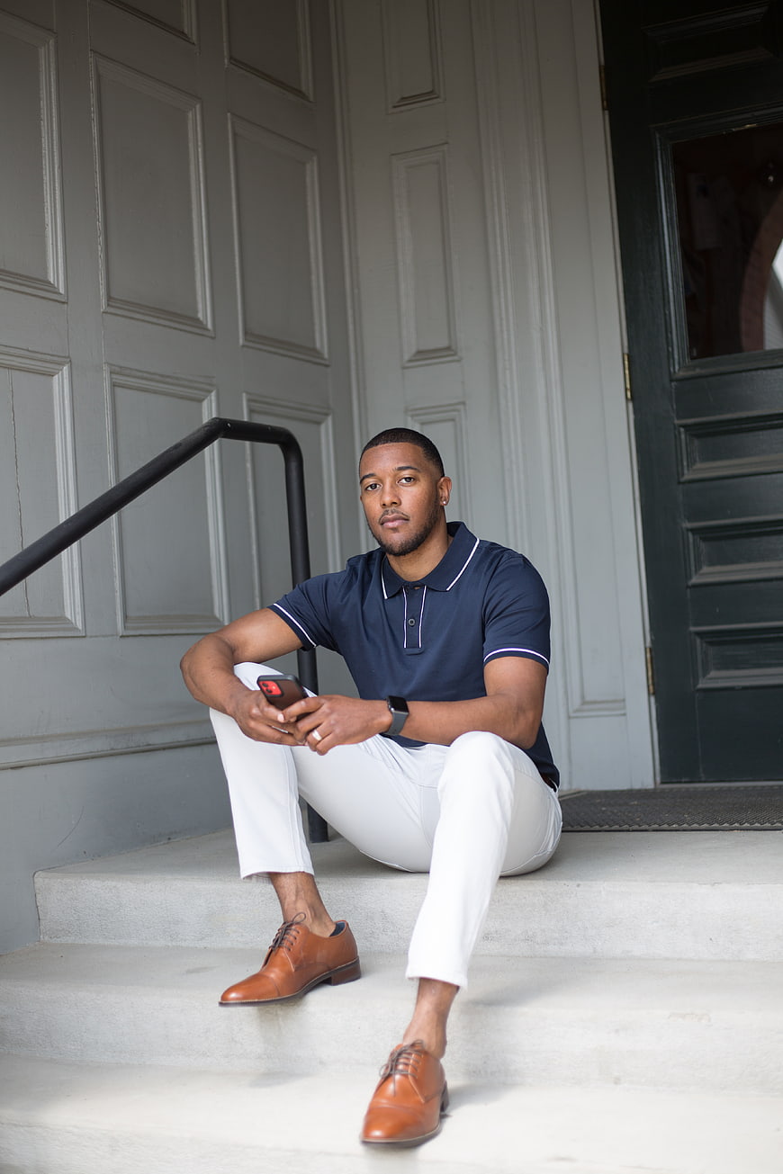 Stylish Black Man Sitting on Steps with Smartphone