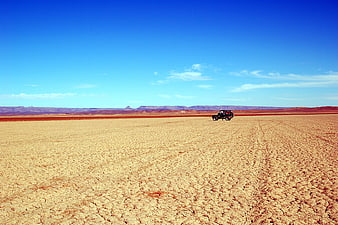 Lone off-road vehicle on vast cracked desert landscape in Morocco