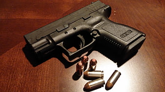 Black semi-automatic pistol with bullets on wooden table