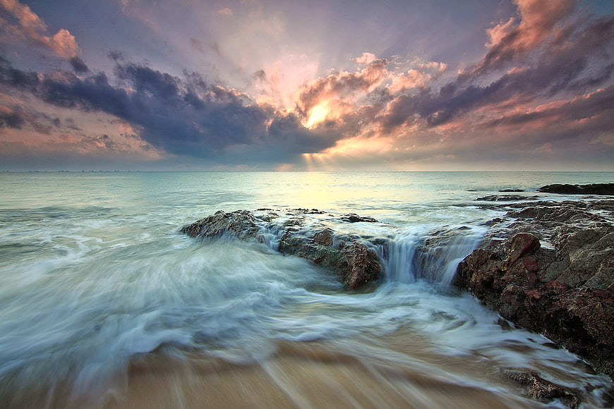 Dramatic Sunset Over Rocky Coast with Long Exposure Waves