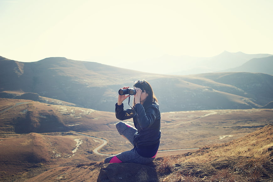 Woman with binoculars overlooking mountain landscape