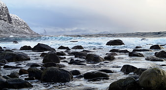 Dramatic Winter Coastal Landscape with Crashing Waves and Snowy Mountains