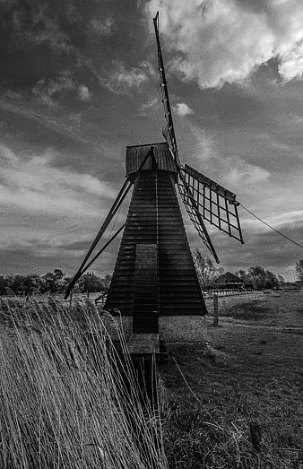 Black and white photo of old wooden windmill in rural landscape