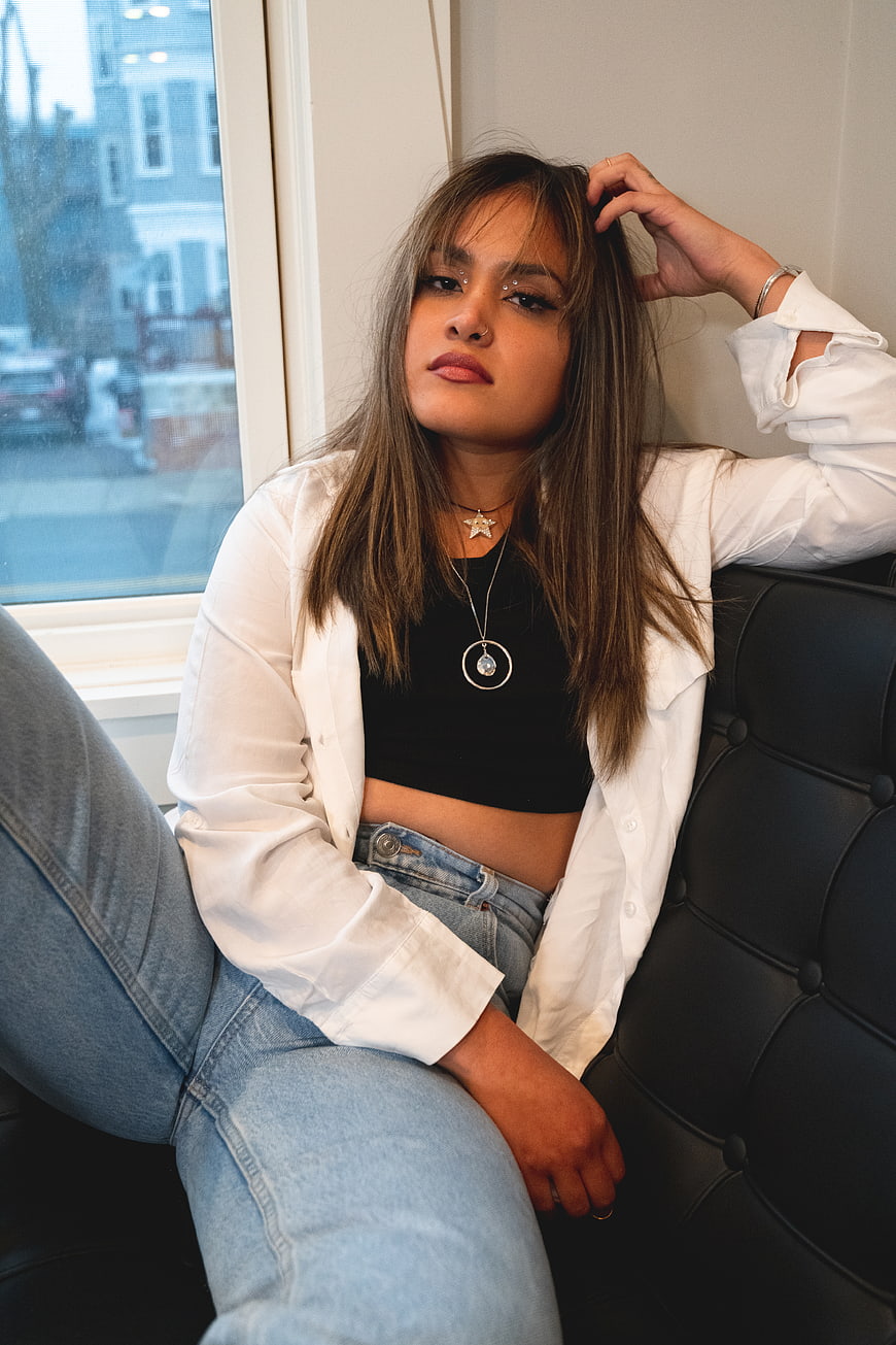 Stylish woman with bangs posing on black leather couch