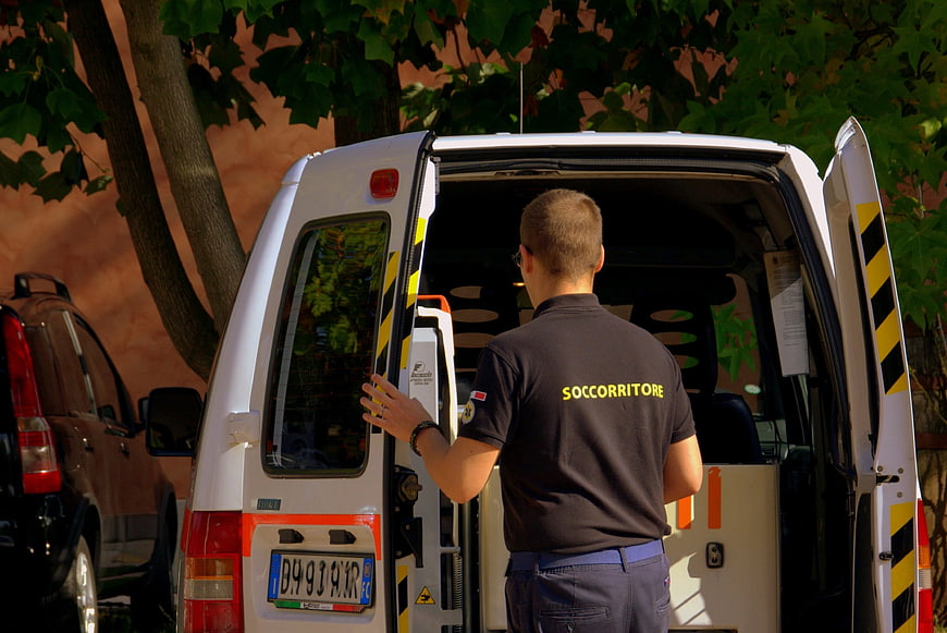 Paramedic in dark uniform standing at open ambulance van rear doors