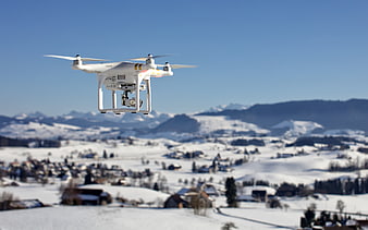 White drone flying over snowy mountain village landscape