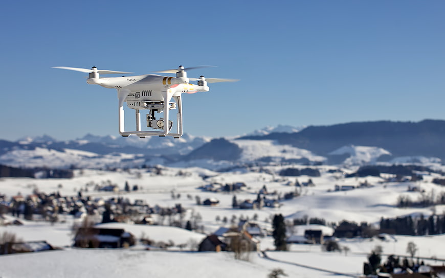 White drone flying over snowy mountain village landscape