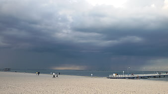 Dramatic Storm Clouds Over Beach with People Walking