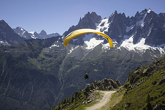 Yellow Paraglider Soaring Over Snowy Mountain Peaks