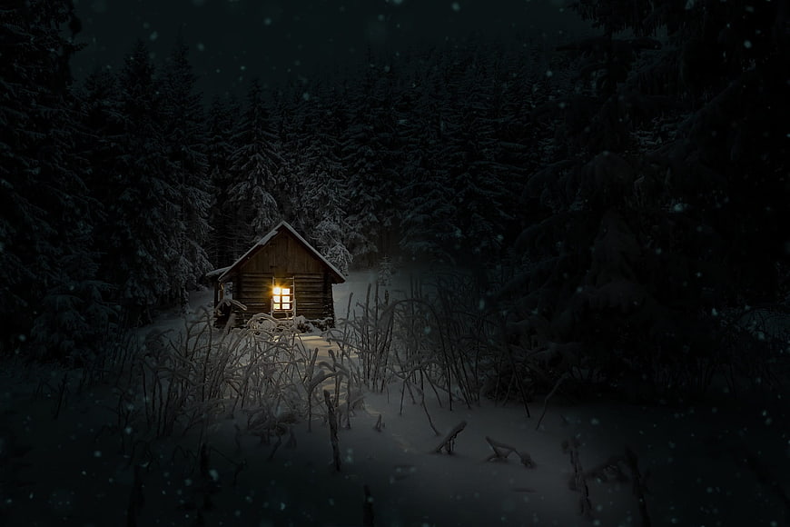 Cozy wooden cabin with glowing window in snowy winter forest at night