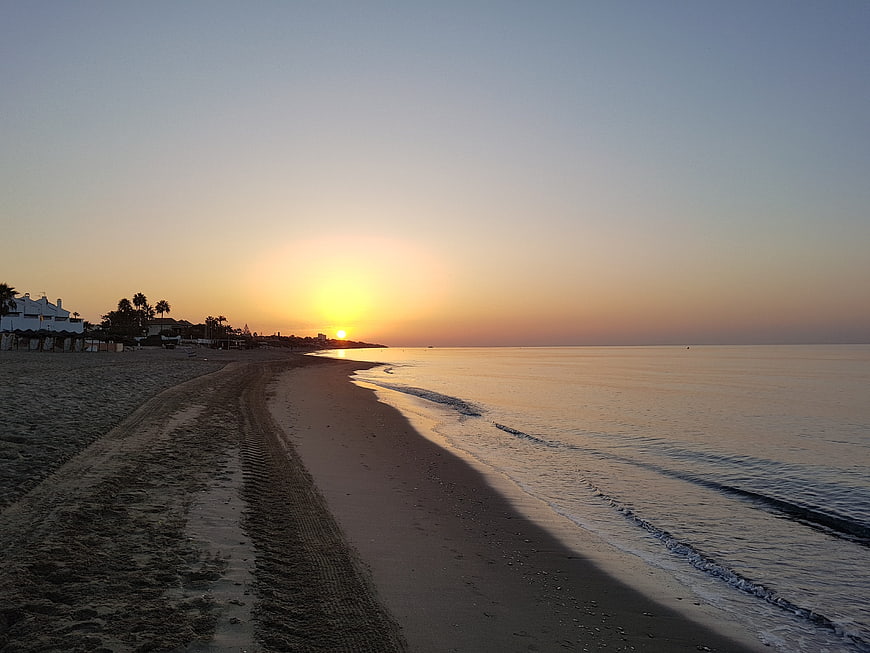 Serene Sunrise Over Sandy Beach With Tire Tracks