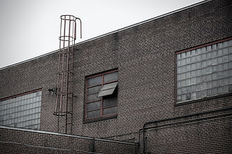 Weathered brick industrial building with metal ladder and glass block windows