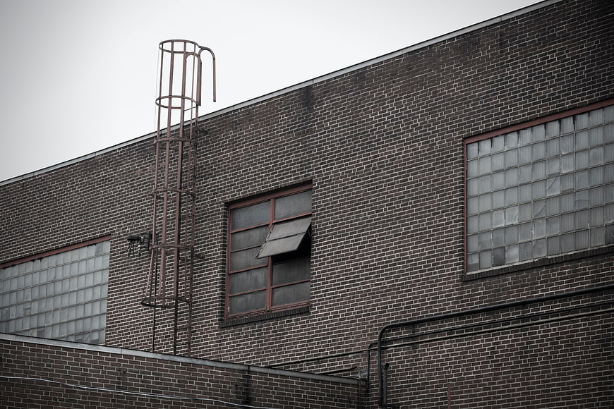 Weathered brick industrial building with metal ladder and glass block windows
