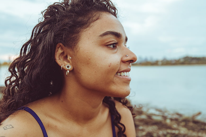 Smiling Woman with Curly Hair in Profile by the Water