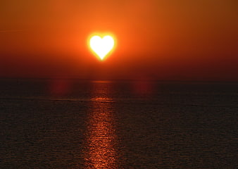 Heart-shaped sunset over calm ocean water