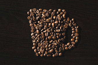 Coffee beans arranged in a mug shape on dark wood