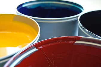 Close-up of open paint cans with vibrant red, yellow, blue, and black paint