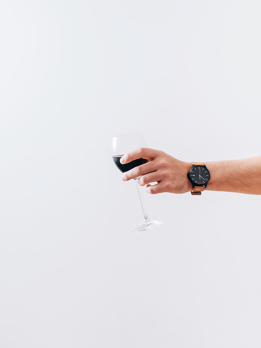 Hand Holding Red Wine Glass with Watch on White Background