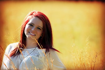 Smiling woman with red hair in a golden field