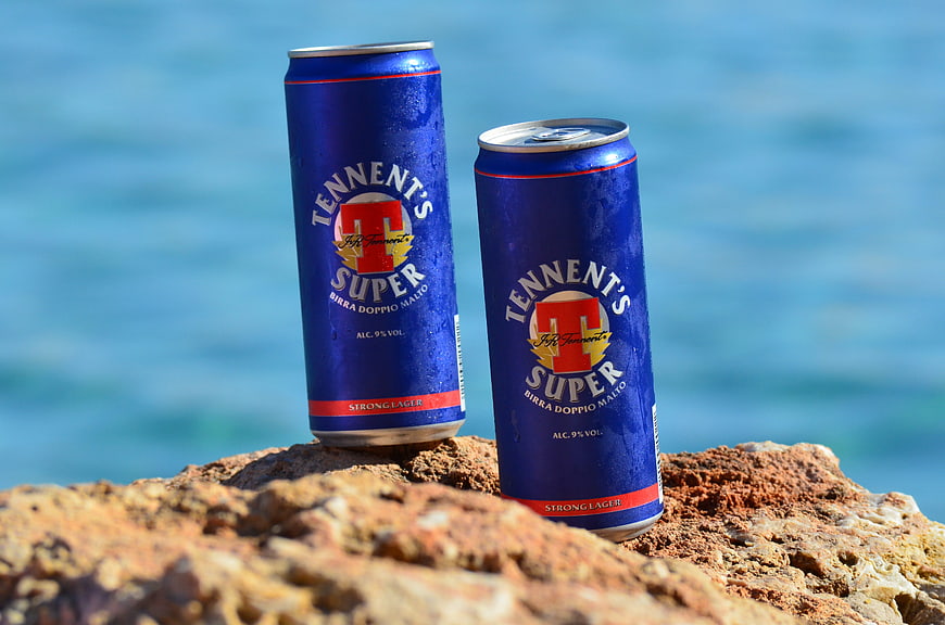 Two Cans of Tennent's Super Beer on a Rocky Coast