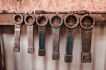 Vintage rusty wrenches hanging on wooden rack in workshop
