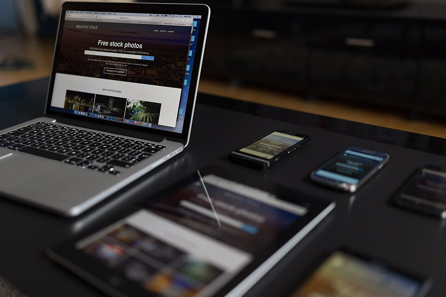 Laptop and smartphones displaying website on dark table