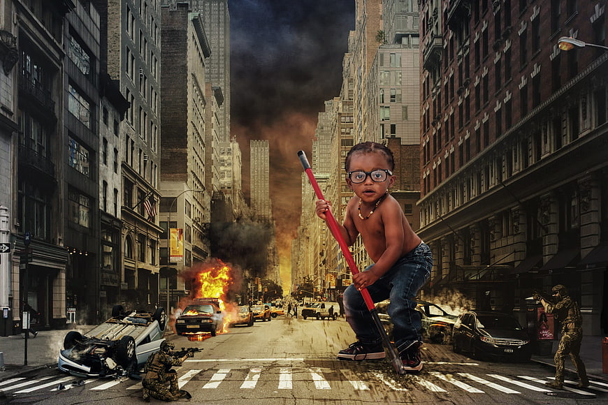 Toddler with red staff in burning city street with soldiers