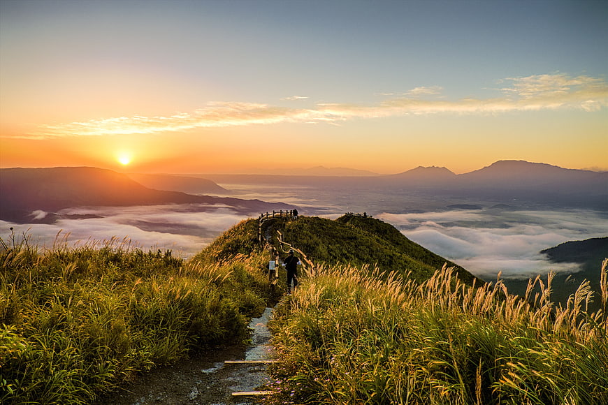 Hikers on Mountain Trail at Sunset Above Sea of Clouds