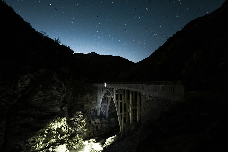 Night Sky Over Stone Arch Bridge in Mountain Canyon