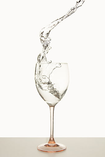 Water Splash Pouring into Clear Wine Glass on White Background