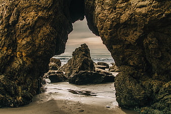 Dramatic View Through Rocky Cave Arch to Ocean Waves