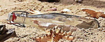 Glass message in a bottle on sandy beach with starfish