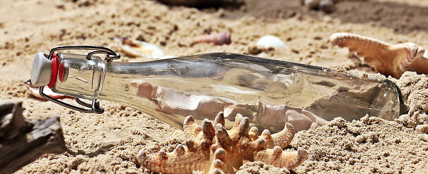Glass message in a bottle on sandy beach with starfish