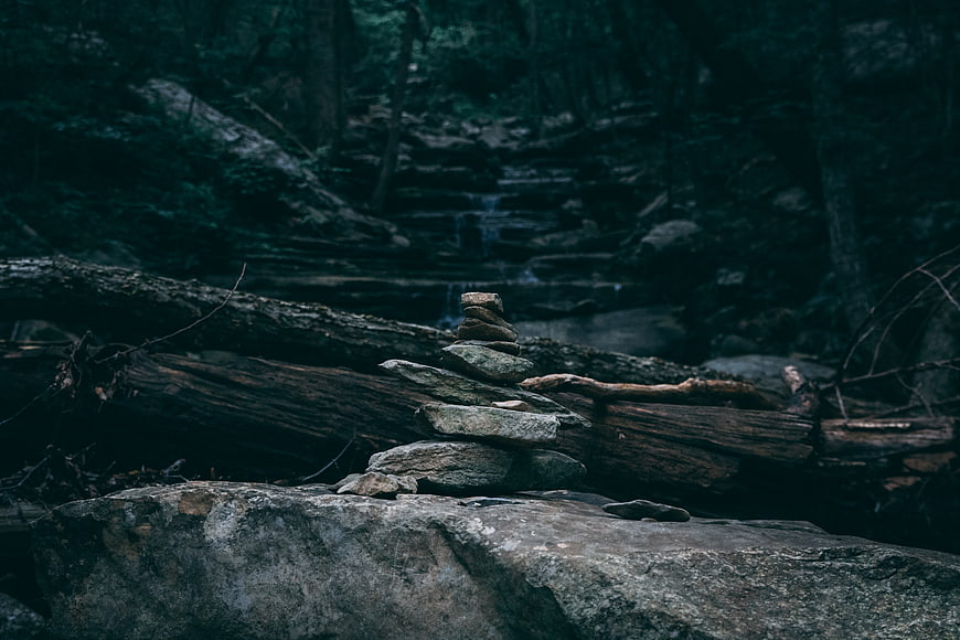 Stacked stones in a dark moody forest with waterfall background