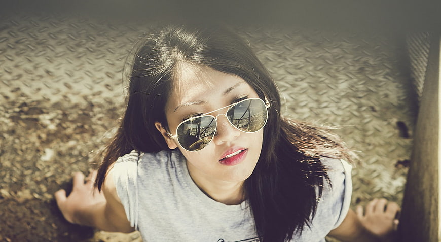 Young Asian Woman Wearing Sunglasses Lying On Ground