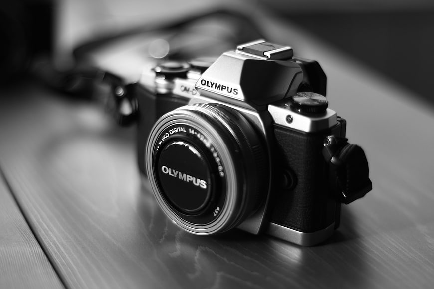 Black and White Olympus Mirrorless Camera on Wooden Table