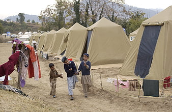 Children playing in a refugee camp with tents