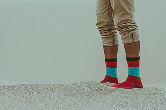 Man Wearing Colorful Socks Standing on Sand