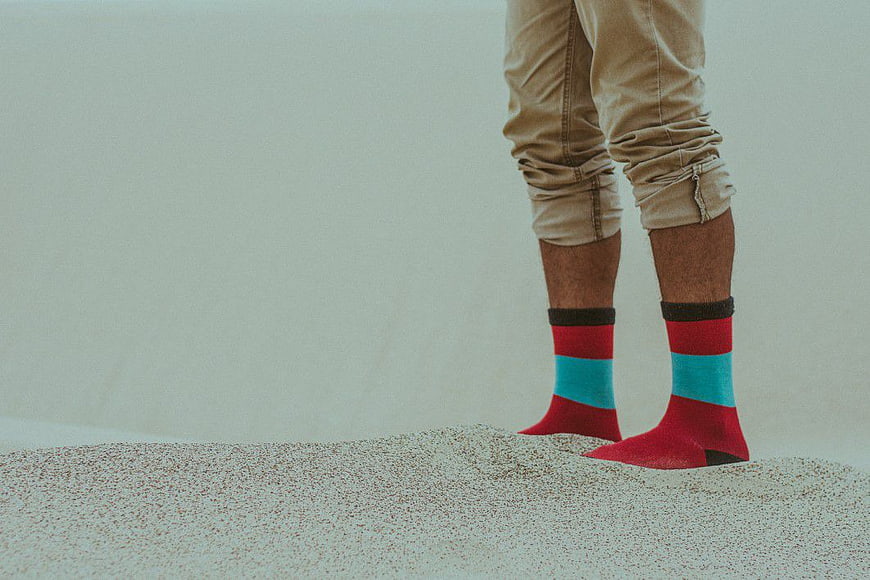 Man Wearing Colorful Socks Standing on Sand