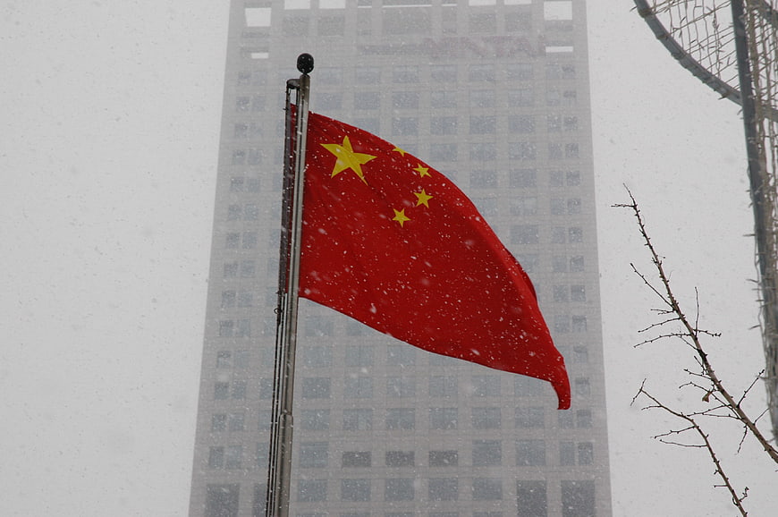 Chinese flag waving in snow against city building