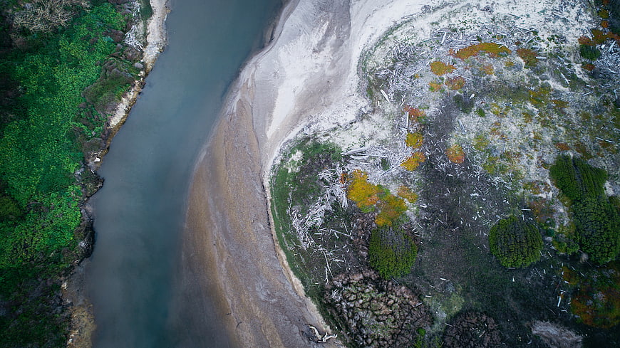 Aerial View of River Meandering Through Forest and Clearcut