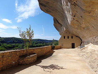 Stone building built into a massive rock overhang with scenic view