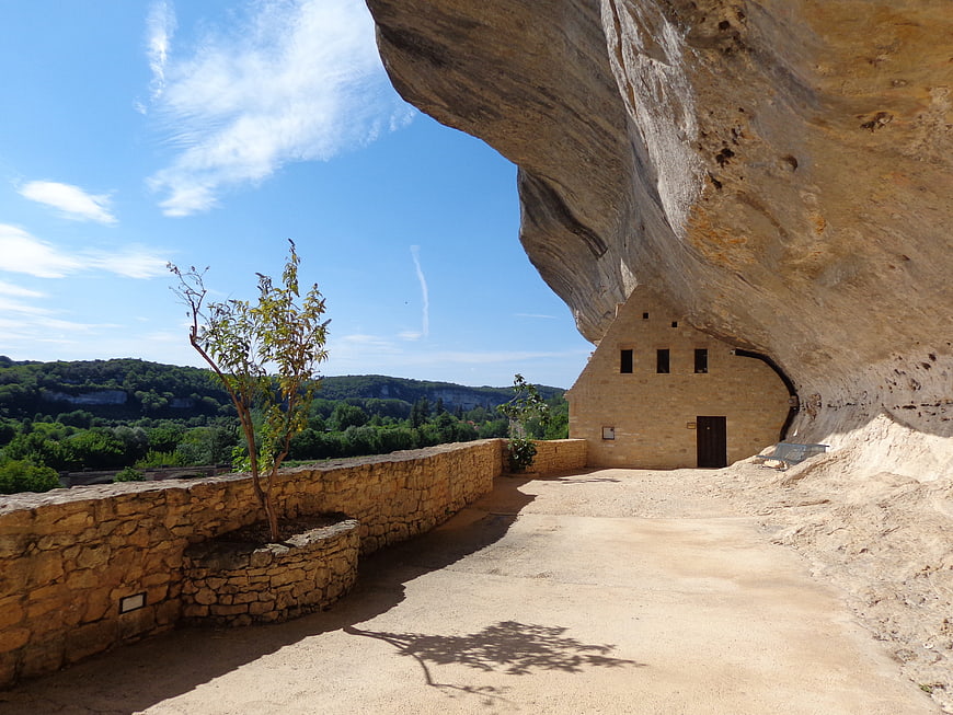 Stone building built into a massive rock overhang with scenic view